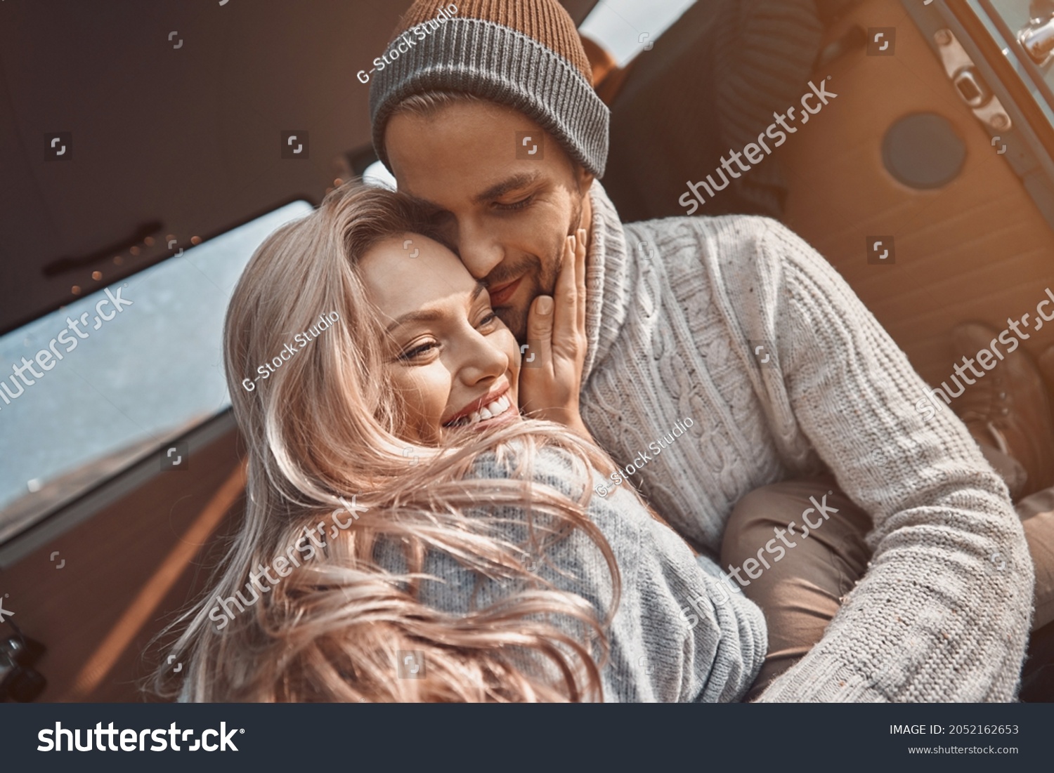 Beautiful young loving couple embracing and smiling while spending time in their minivan #2052162653