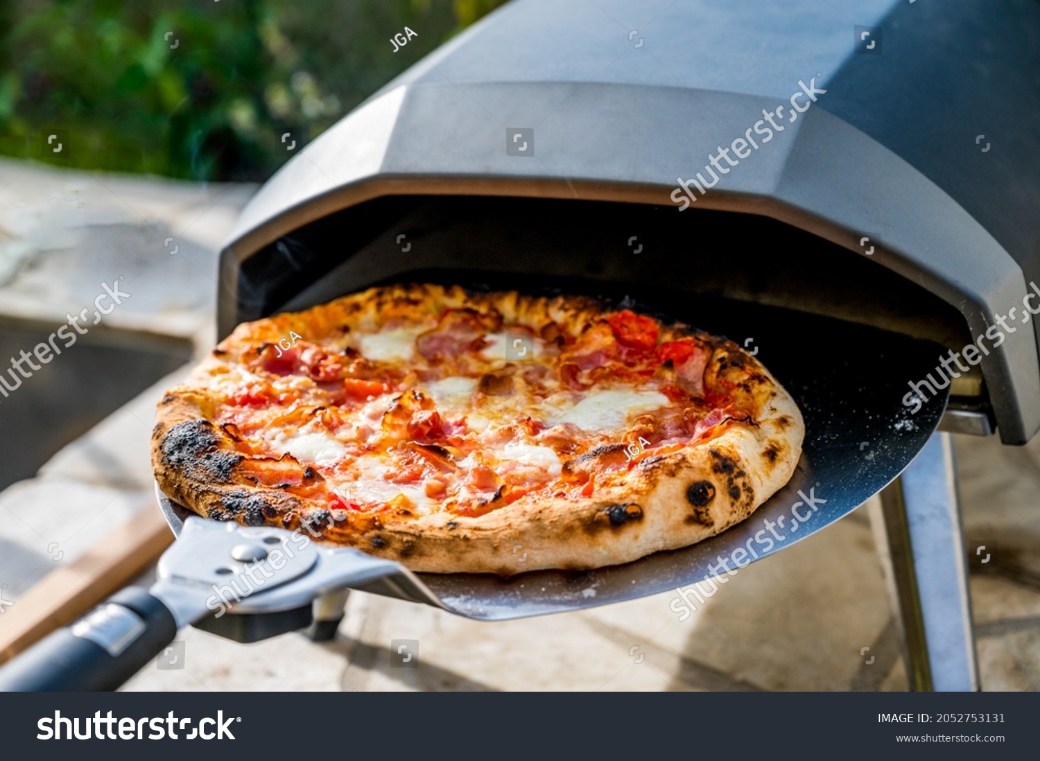 Making homemade pizza in portable high temperature gas  oven. Delicious pizza is baking in gas oven furnace for home made Neapolitan pizza. Special gas fueled pizza oven for picnic or party. #2052753131