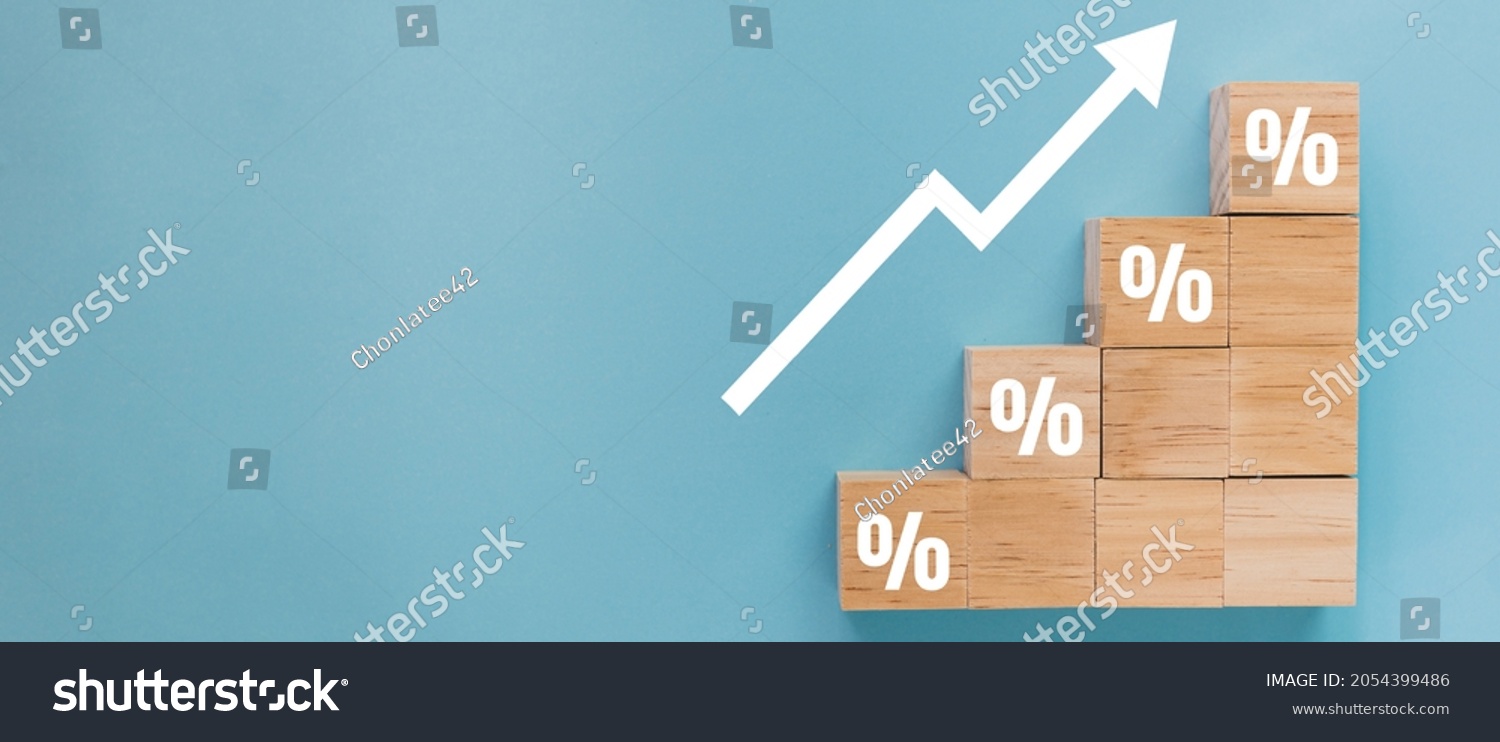 Wooden block signs and symbols with percentage sign and up arrow financial and business growth interest rates and mortgage rates interest on investment inflation concept on blue background. #2054399486