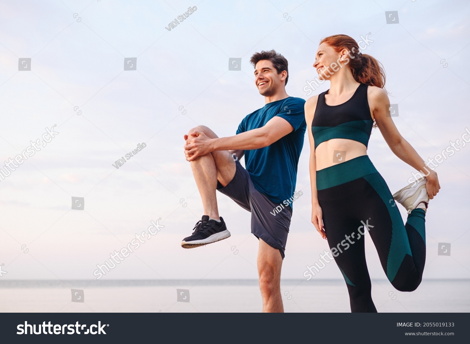 Lower couple young two friend strong sporty sportswoman sportsman woman man in sport clothes warm up training do stretch exercise on sand sea ocean beach outdoor jog on seaside in summer day morning #2055019133