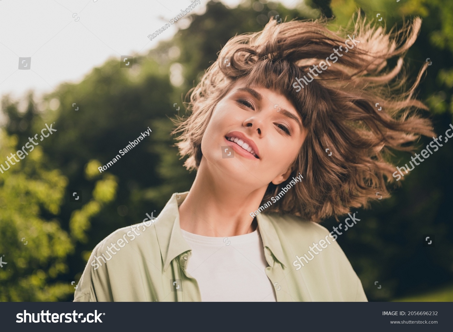 Photo portrait young girl with smiling throwing hair outdoors in summer sunny green park #2056696232