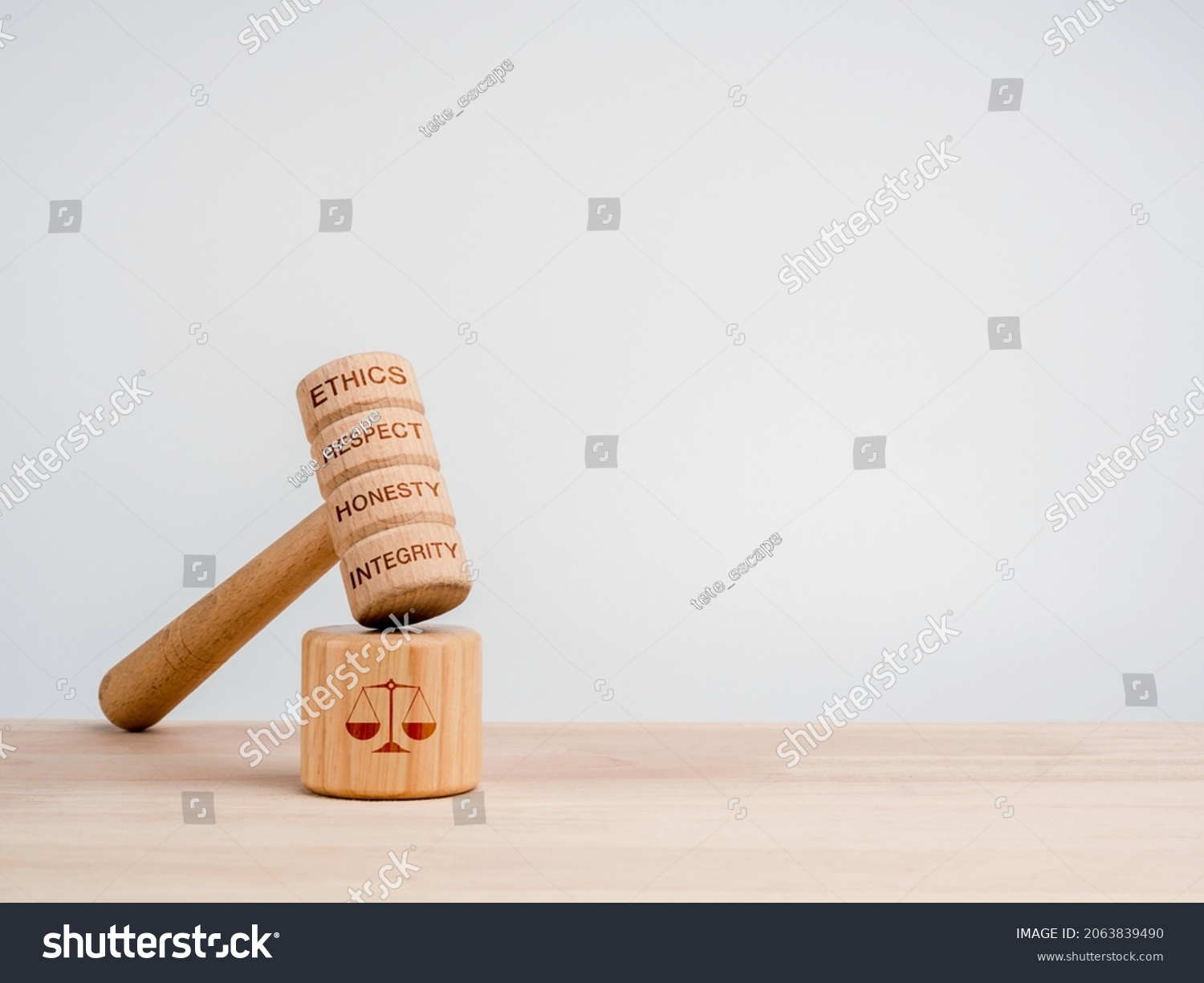 A wooden judge gavel with words, ethics, respect, honesty, and integrity with the soundboard with scales icon, toys on wooden table, white background with copy space, minimal style. Justice concept. #2063839490