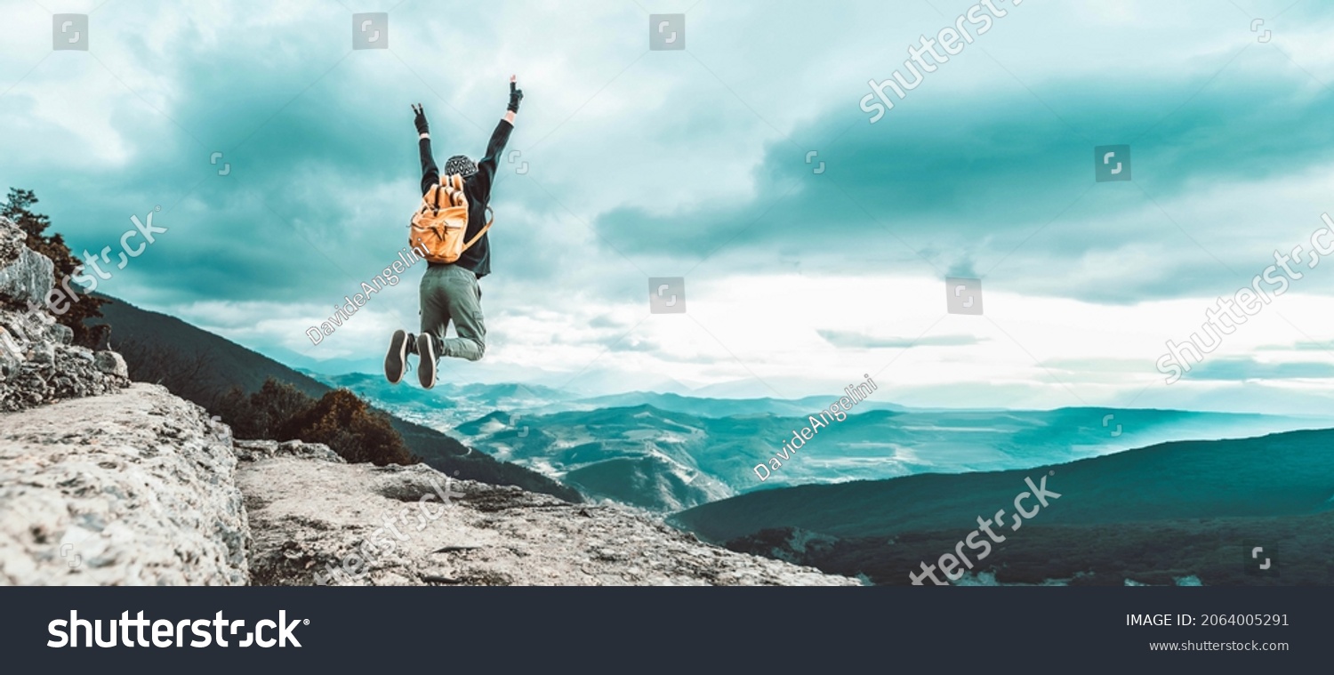 Man traveler on mountain summit enjoying nature view with hands raised over clouds - Sport, travel business and success, leadership and achievement concept #2064005291