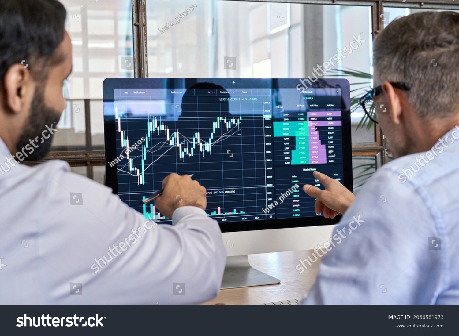 Two traders brokers stock exchange market investors discussing crypto trading charts growth using pc computer pointing at screen analyzing financial risks, investment profit forecast. Over shoulder #2066581973