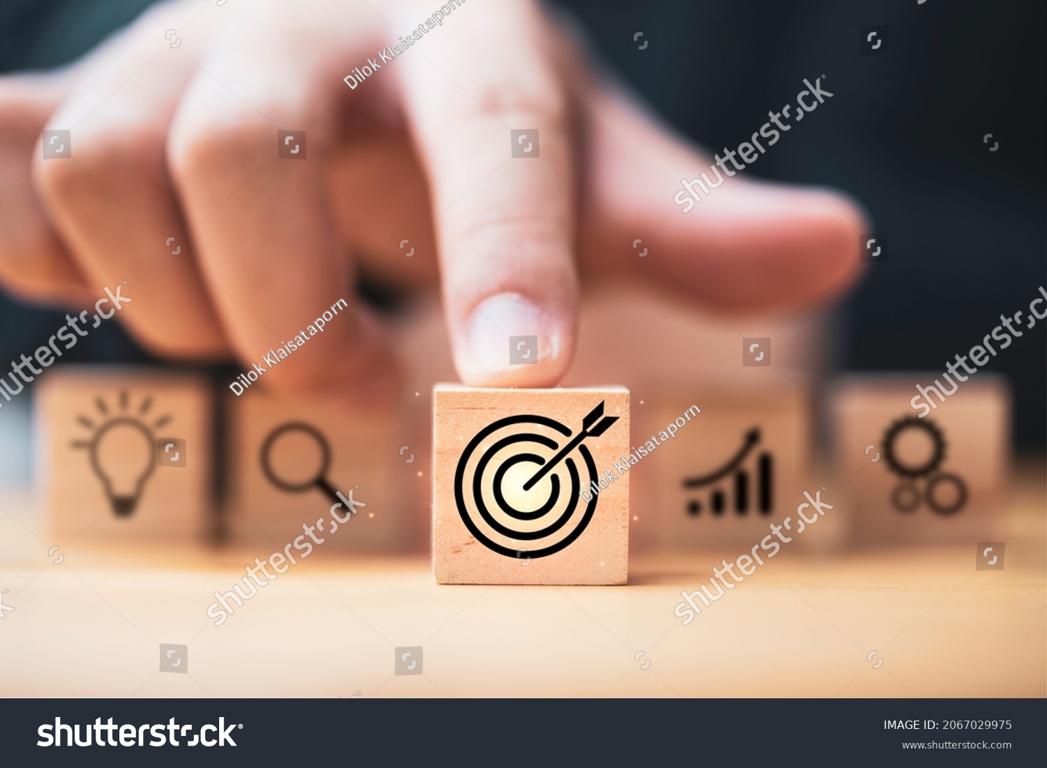 Hand  touching and push target board which printing on wooden cube block on mechanical gear and lightbulb icon  for creative and set up business objective target  goal concept. #2067029975