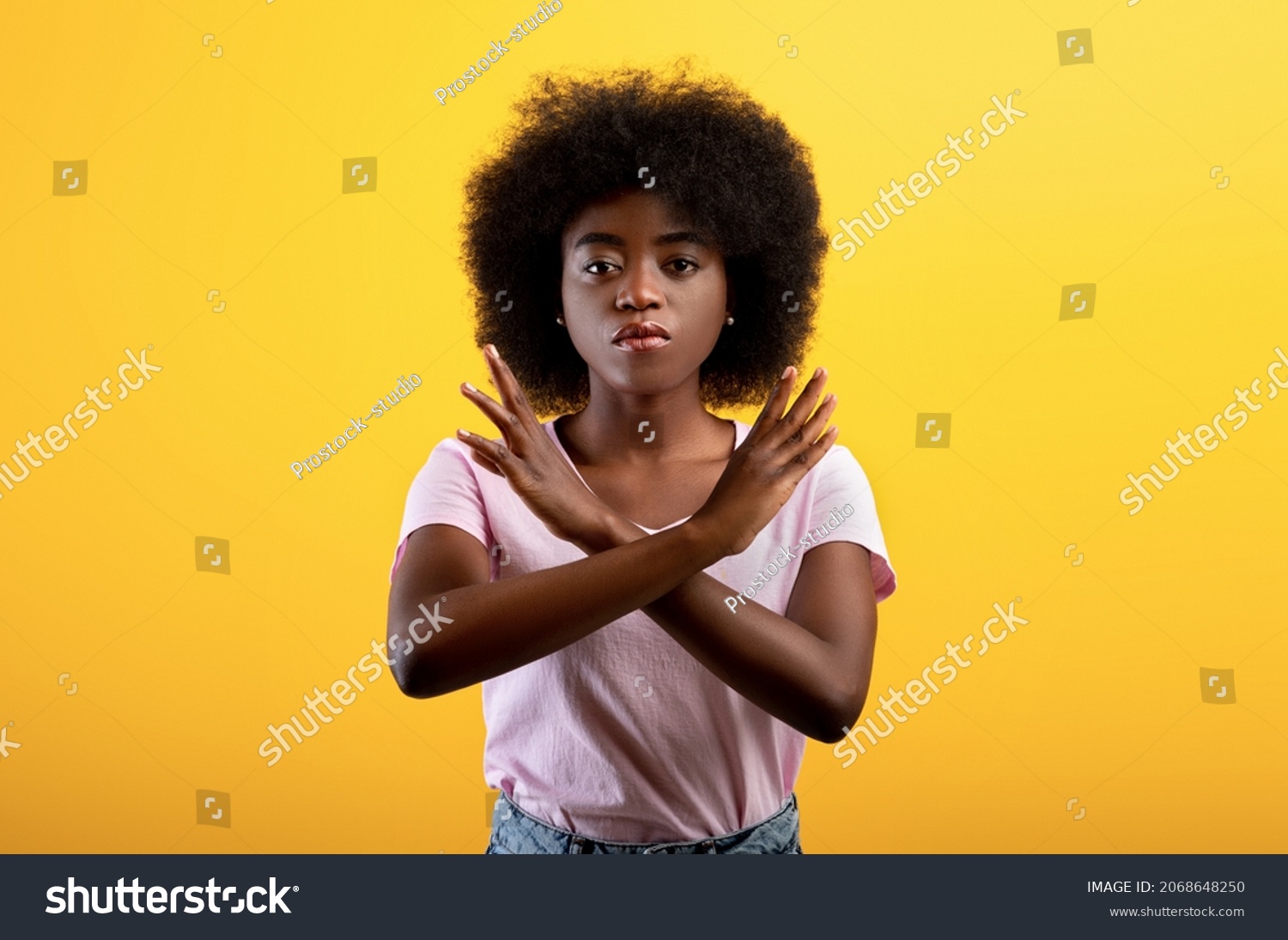 Refusal concept. Upset black lady showing stop gesture with crossed hands, refusing something unwanted while standing over yellow studio background #2068648250