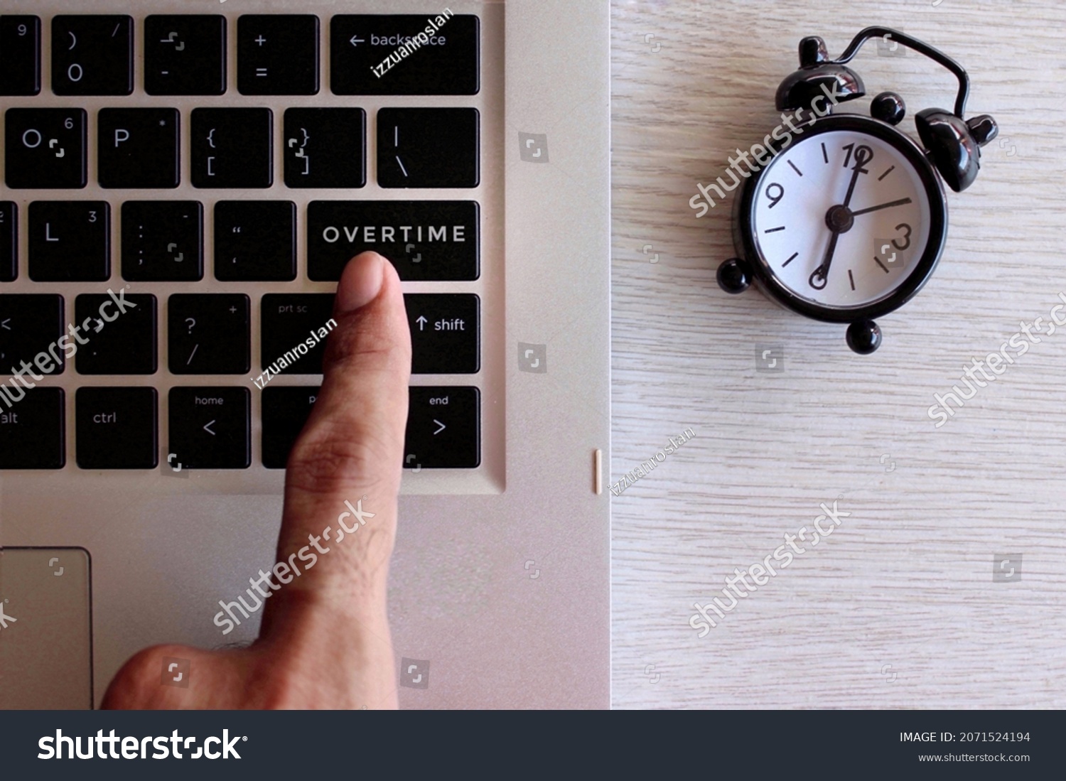 Overtime work concept. Finger pressing keyboard with text OVERTIME and black alarm clock. #2071524194