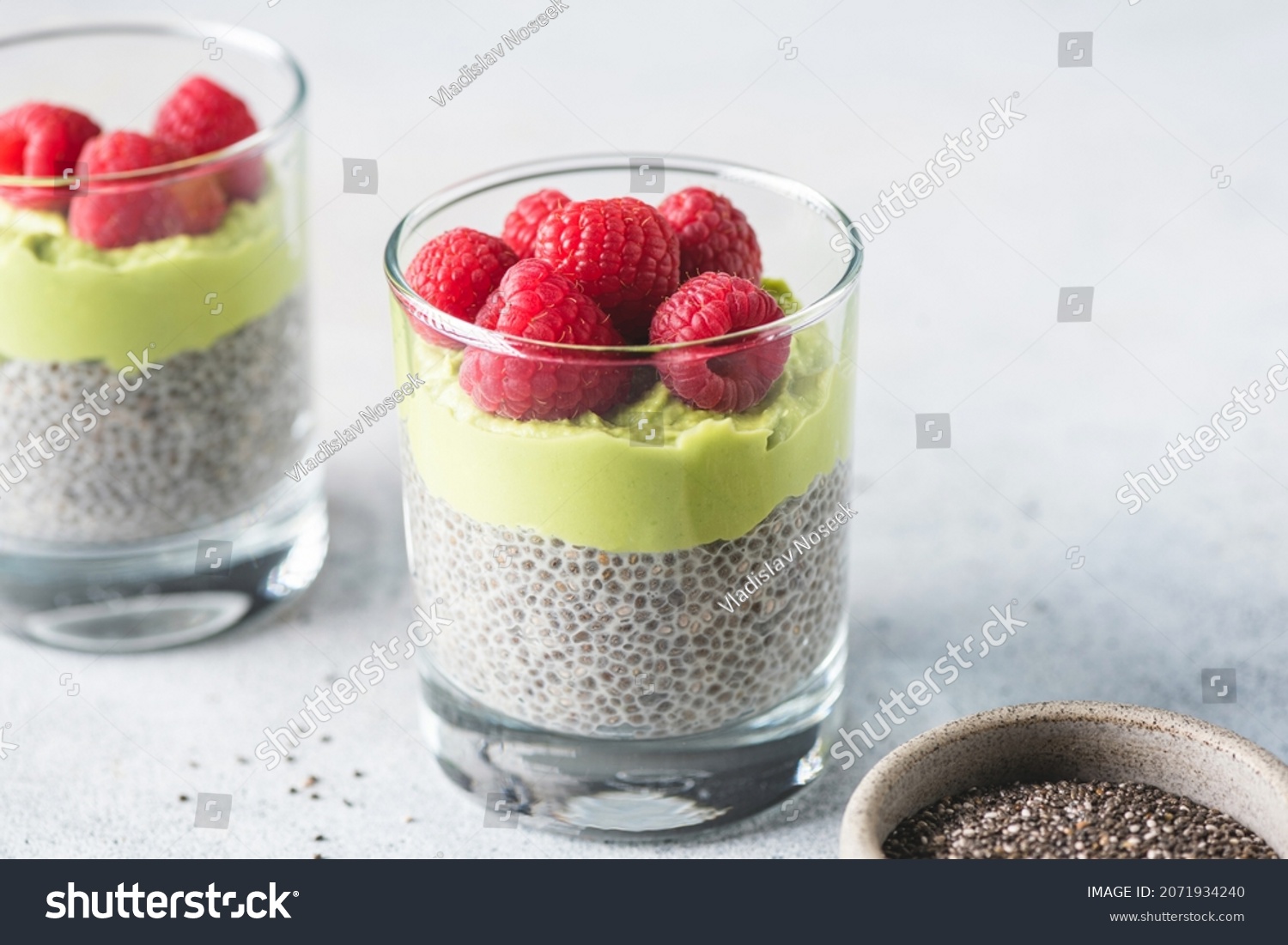 Vegan chia seed pudding with avocado mousse layer and topped with fresh raspberries. Healthy breakfast or snack food rich in Omega 3 fatty acids #2071934240