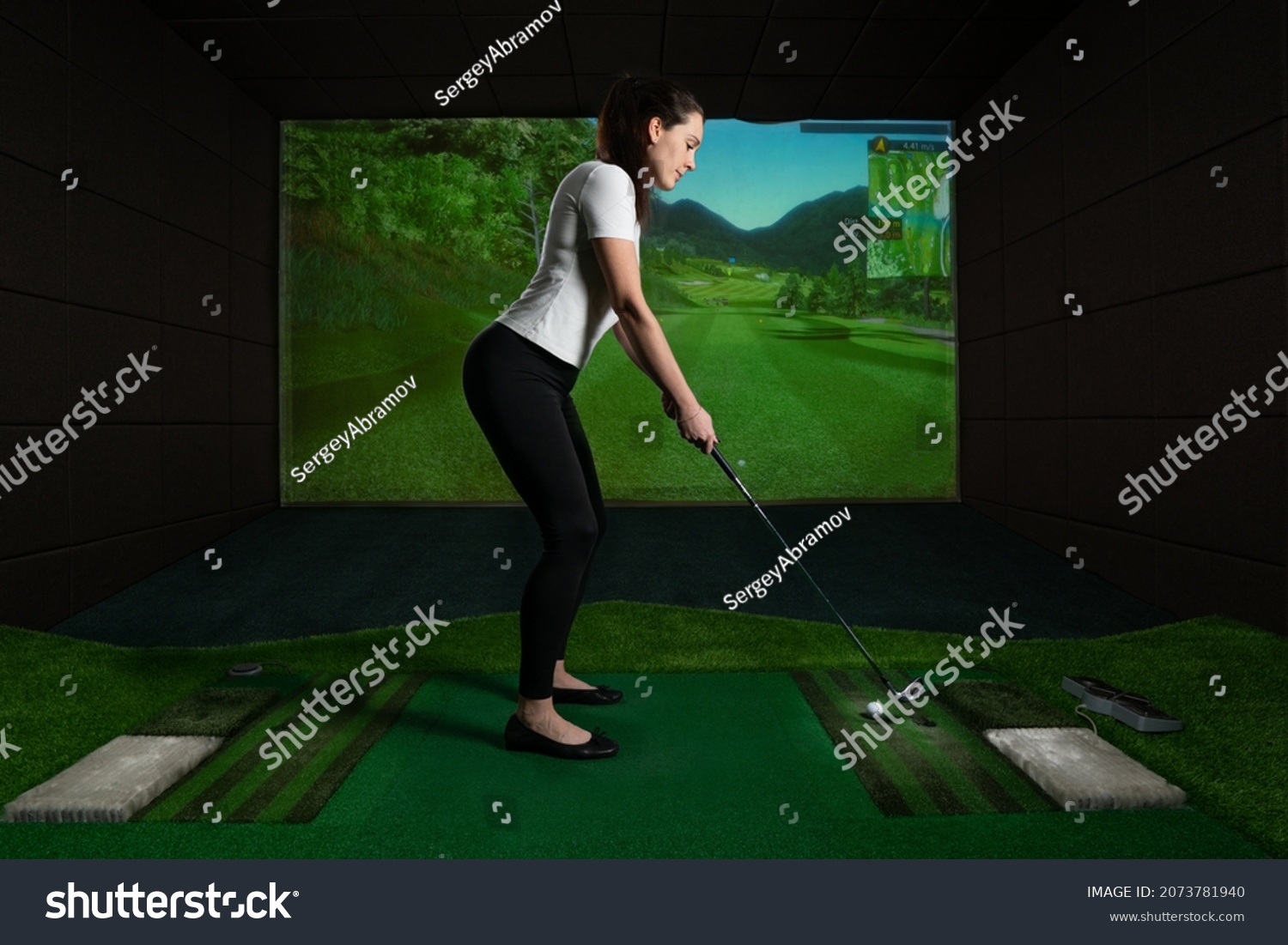 A girl playing screen golf, golf simulator.Young golf player having playing video-game golf indoors.                                                                   #2073781940