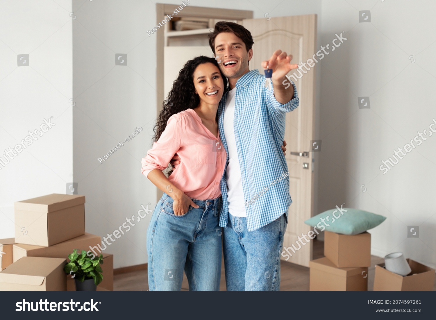 House Ownership. Portrait Of Happy Young Couple Holding Showing Key Standing In New Flat, Cheerful Guy And Lady Posing Hugging After Moving In Own Apartment. Insurance, Real Estate, Mortgage Concept #2074597261