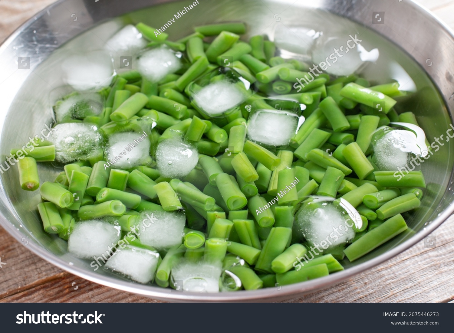 Green beans in a colander. Boiled or blanched vegetables in ice water on a wooden table #2075446273