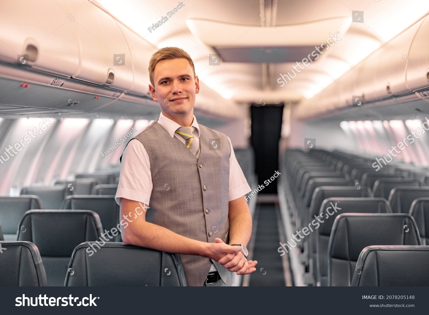 Male flight attendant standing in aircraft passenger salon #2078205148