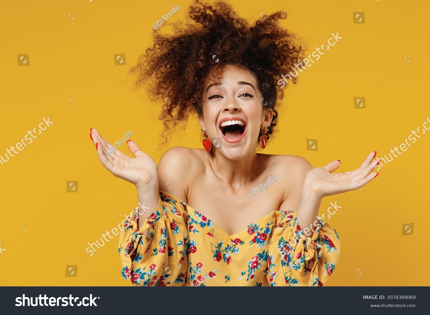 Young happy satisfied excited fun surprised amazed woman 20s with culry hair in casual clothes spread hands look camera isolated on plain yellow background studio portrait. People lifestyle concept #2078389069