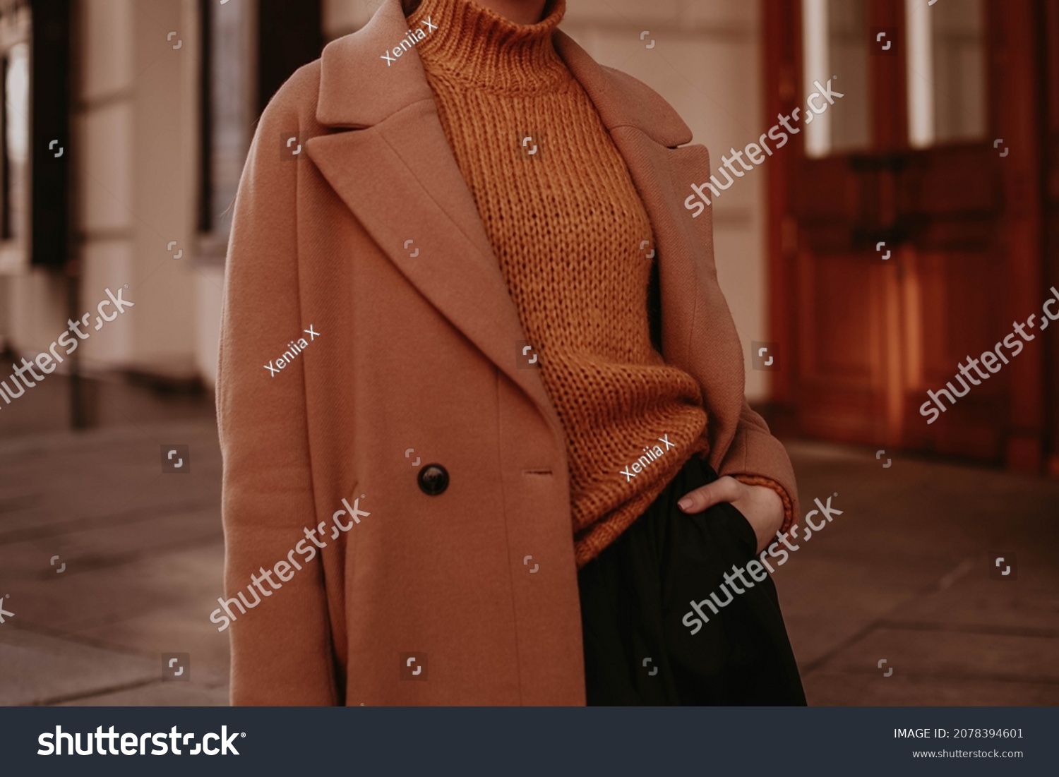 Cropped female figure in a brown cozy warm coat and knitted orange sweater. Street casual winter or autumn fashion. #2078394601