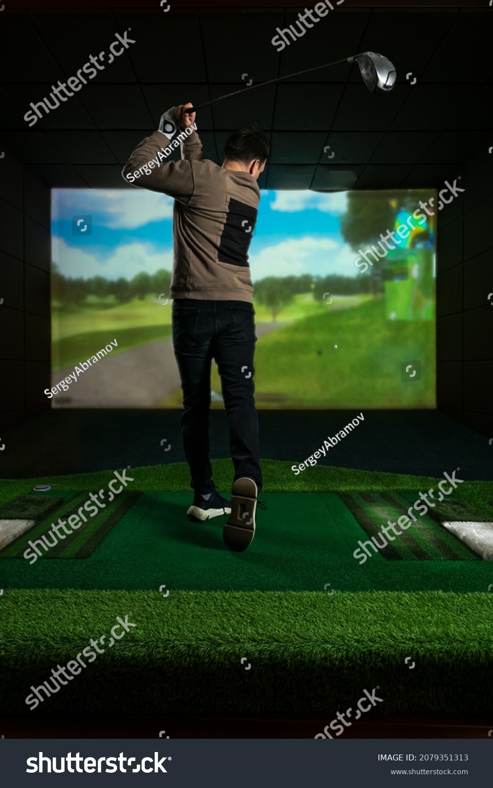 A man playing screen golf. Golf Simulator. Young golf player having playing video-game golf indoors #2079351313