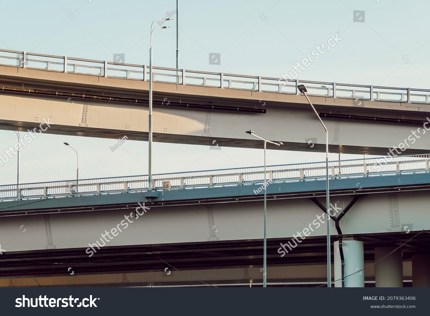 New multilevel road junction, bottom view. Overpasses one above the other. Road fence and road lighting poles #2079363406