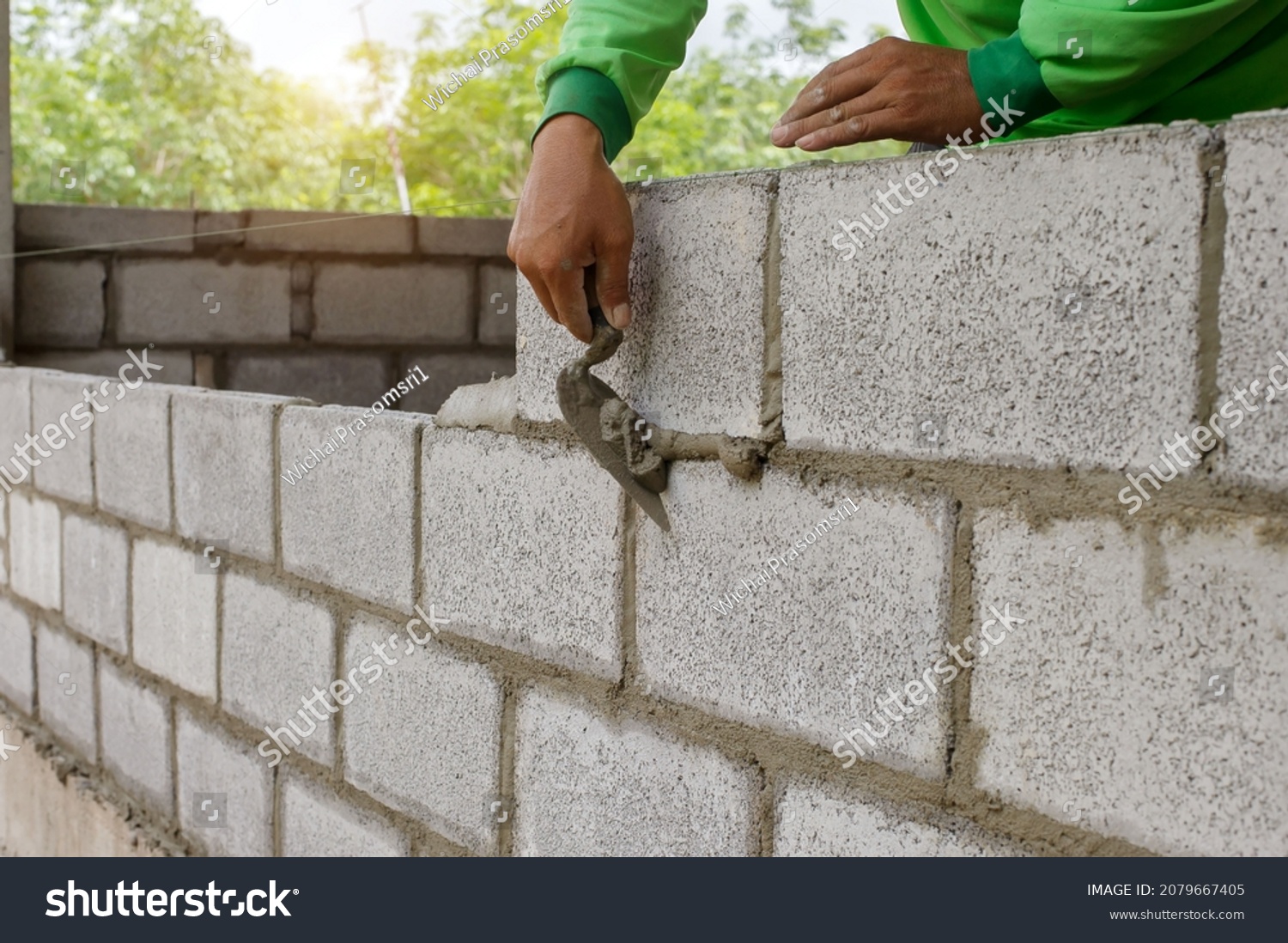 masonry worker make concrete wall by cement block and plaster at construction site #2079667405