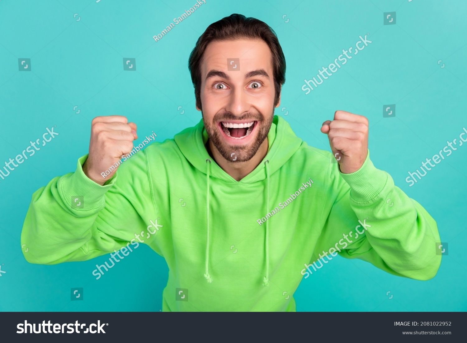Photo of astonished guy celebrate successful bet goal attainment wear green hoodie isolated teal color background #2081022952