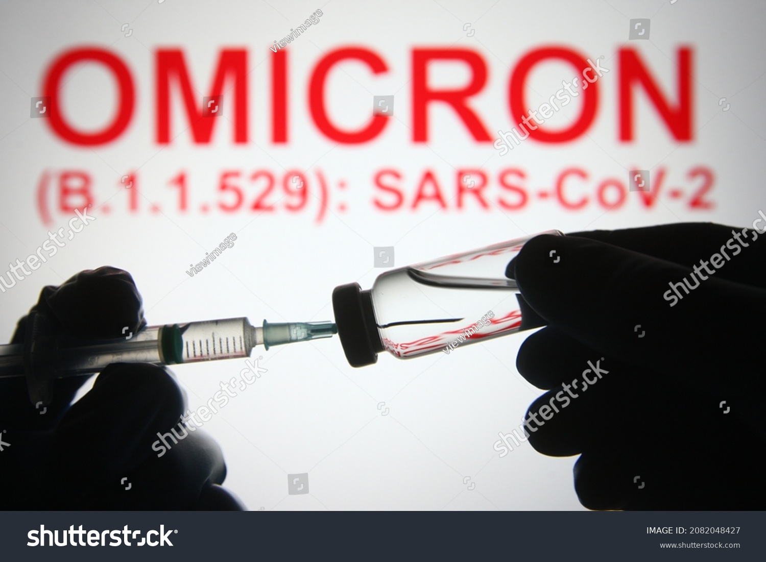 In this photo illustration of a new COVID-19 variant a medical syringe and a vial are seen and Omicron (B.1.1.529): SARS-CoV-2 words in the white background. select focus #2082048427