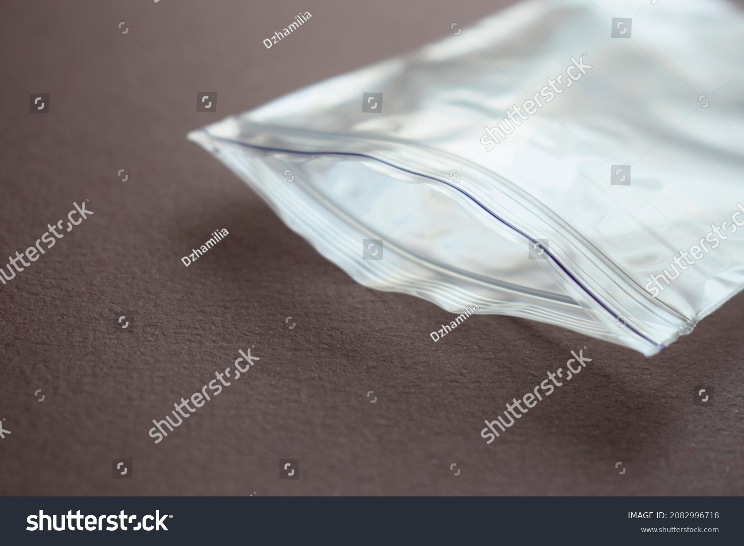 Small transparent plastic bag with zip clasp on a dark background. The clasp is open. #2082996718