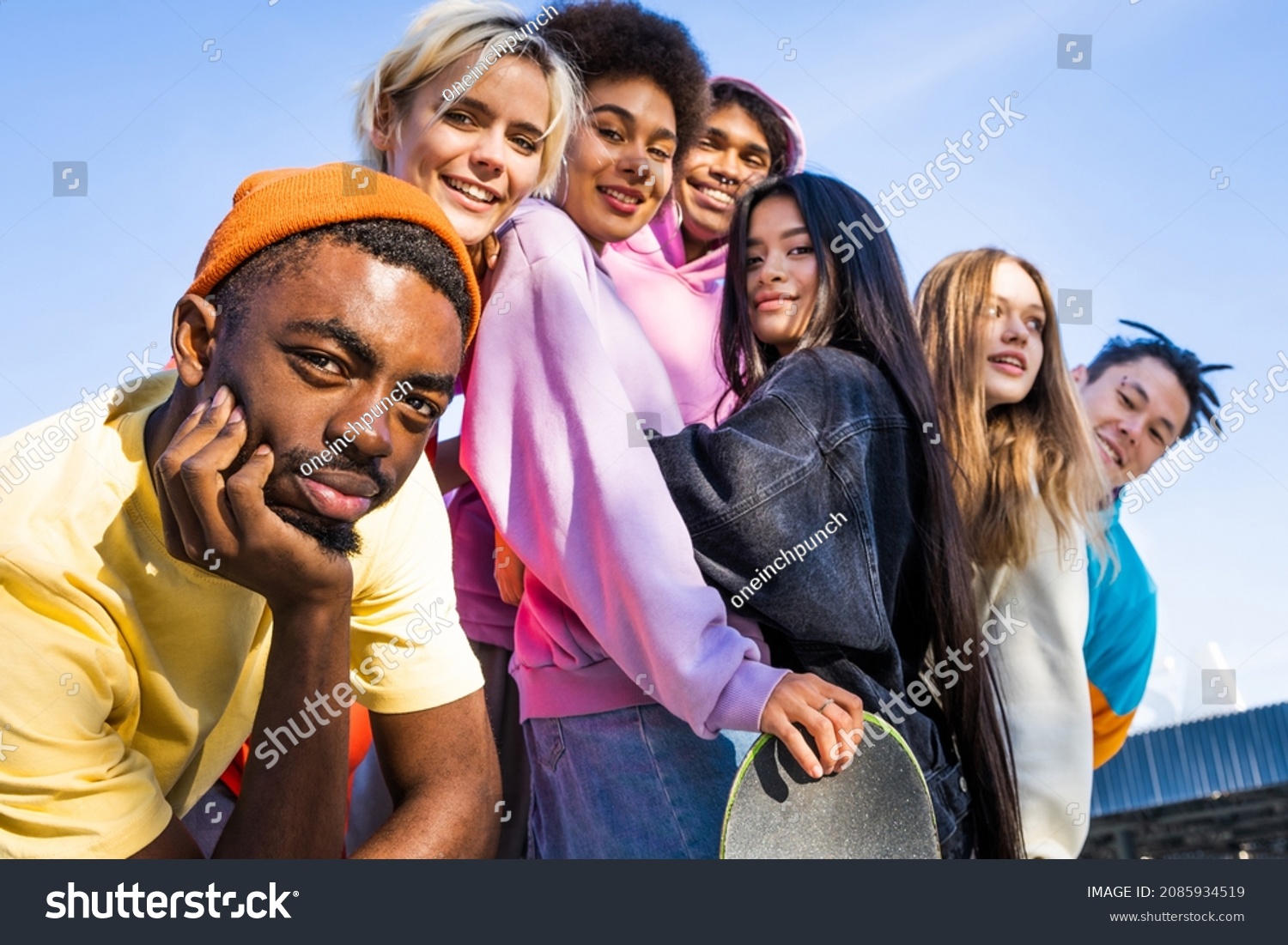 Multicultural group of young friends bonding outdoors and having fun - Stylish cool teens gathering at urban skate park #2085934519