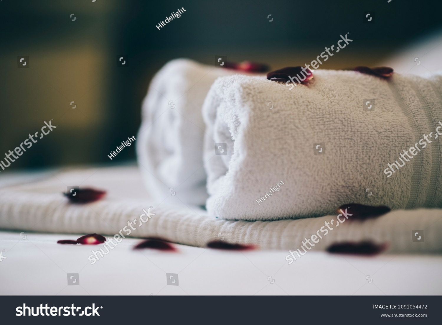 Luxury hotel room with white spa towels on bed sheet with rose petals. Romantic holiday weekend with wellness body treatment  and relax couple massage in honeymoon suite. Closeup. #2091054472