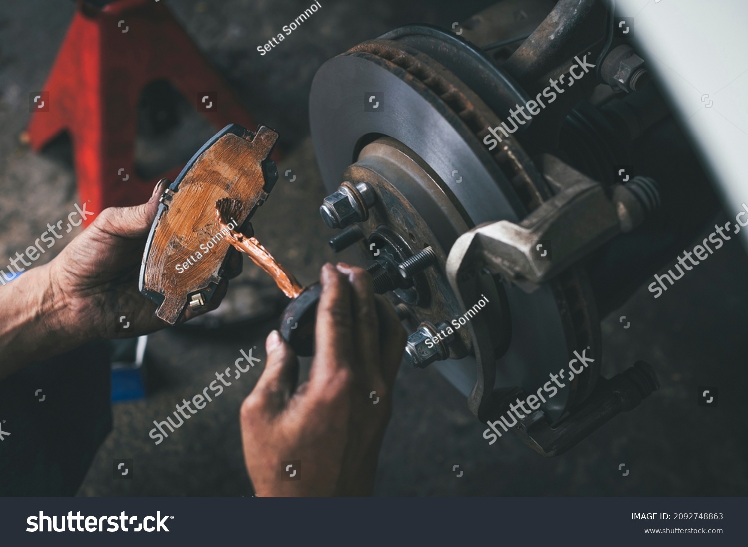 Auto mechanic applying a high temp brake grease on the brake pads. #2092748863