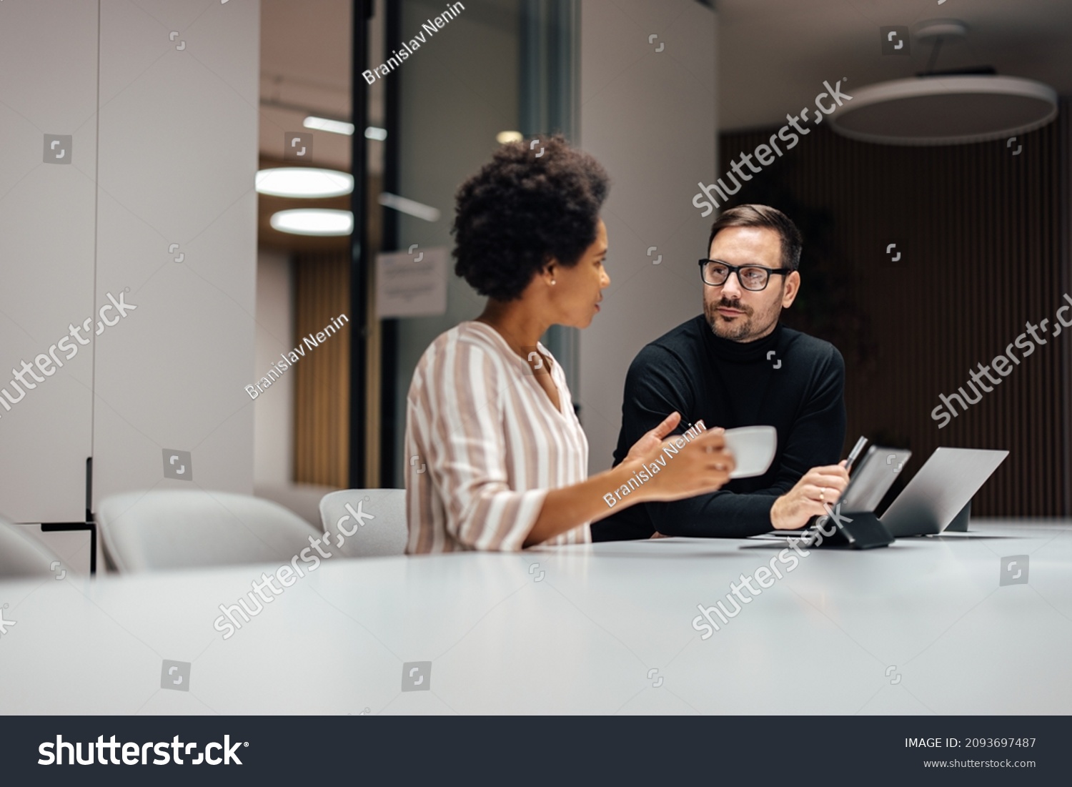 Two diverse employees, taking a breather and talking to each other. #2093697487