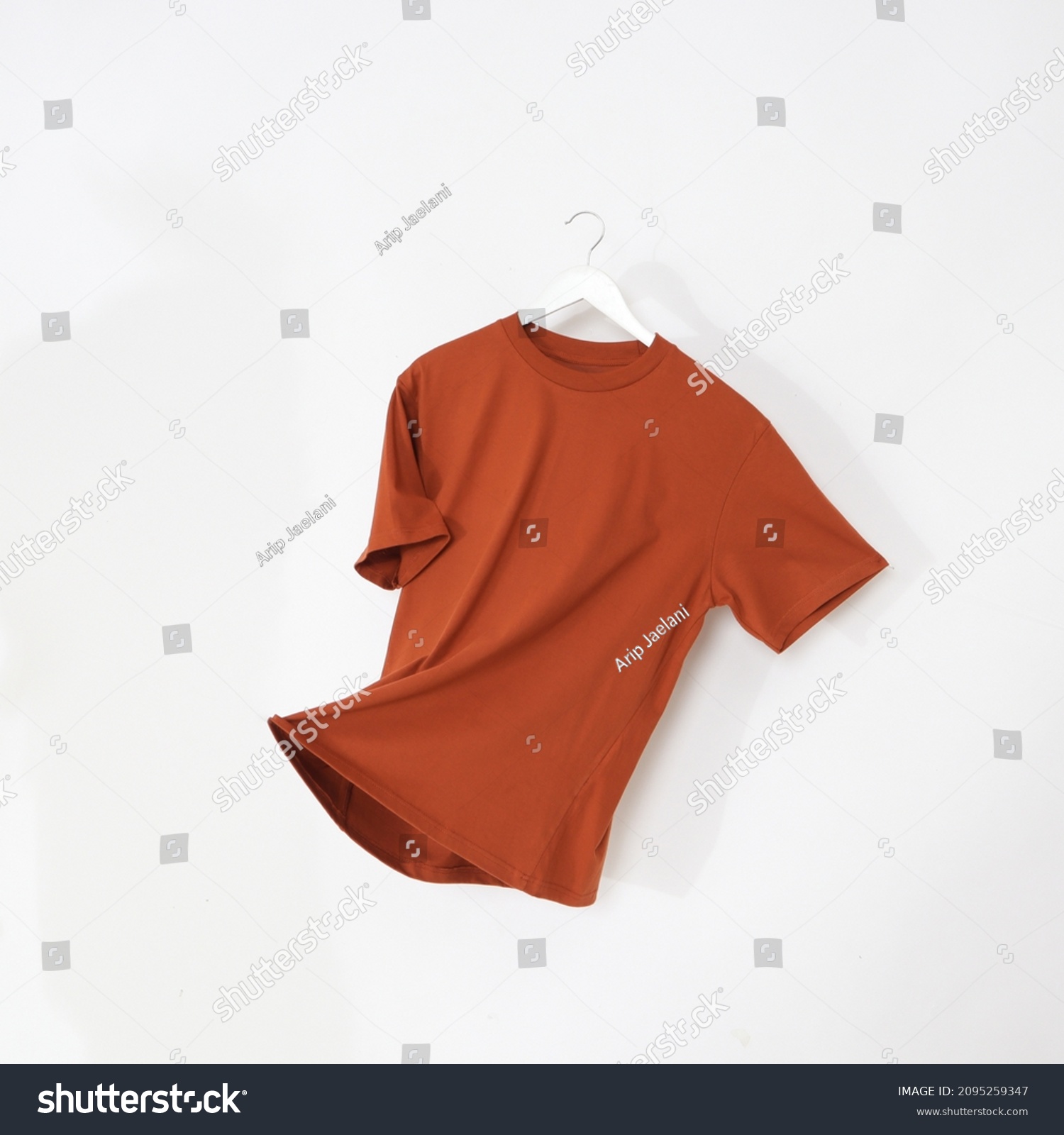 Orange tshirt with hanger. Flying cotton T-shirt isolated on white background. #2095259347