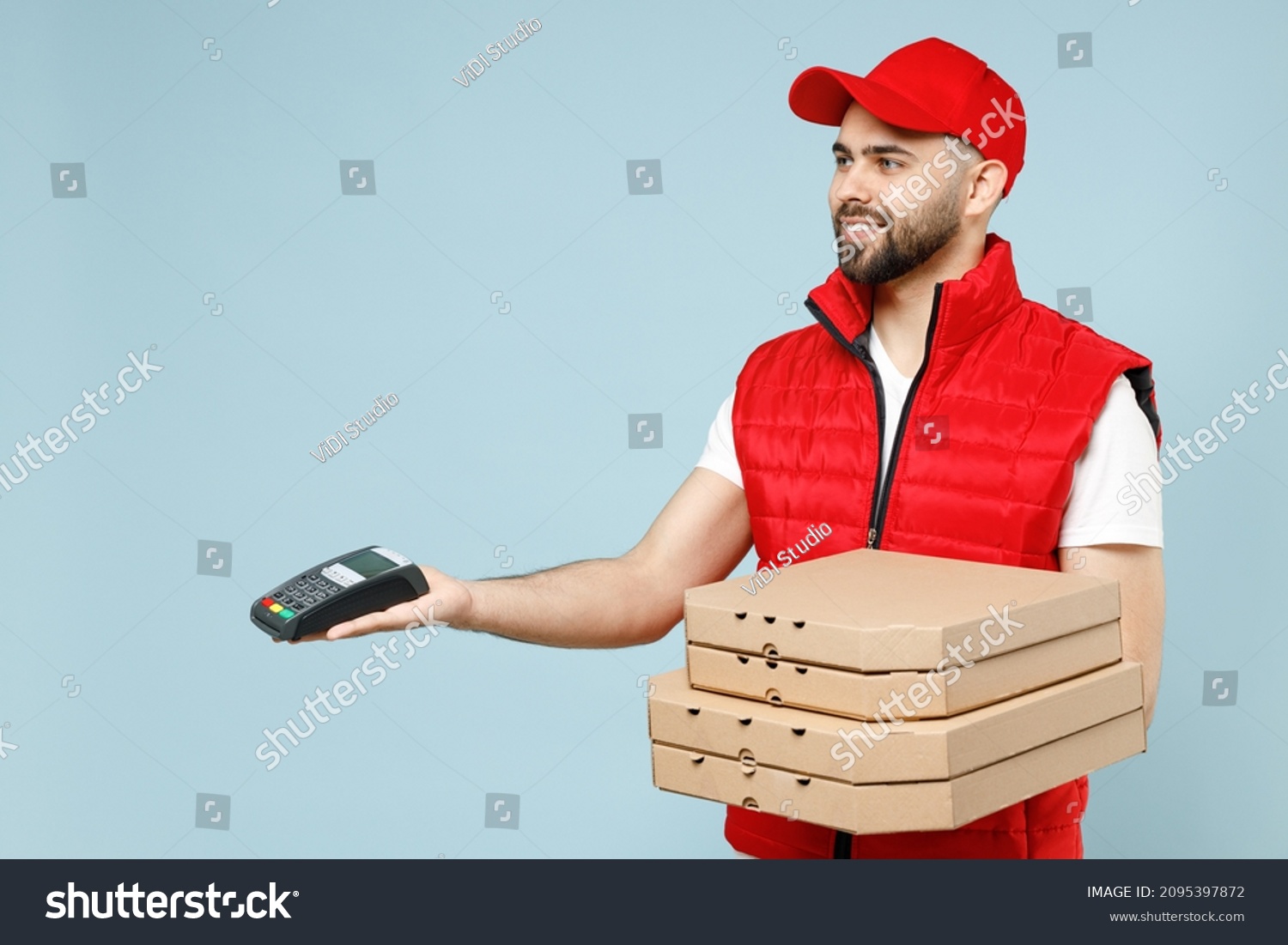 Delivery guy employee man in red cap white T-shirt vest uniform workwear work as dealer courier hold terminal pizza in cardboard flatbox isolated on pastel blue color background studio Service concept #2095397872