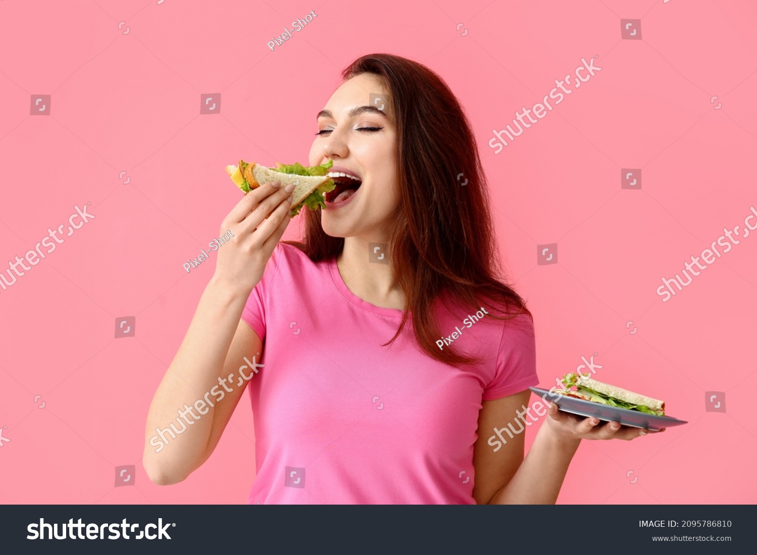 Young woman eating tasty sandwich on color background #2095786810