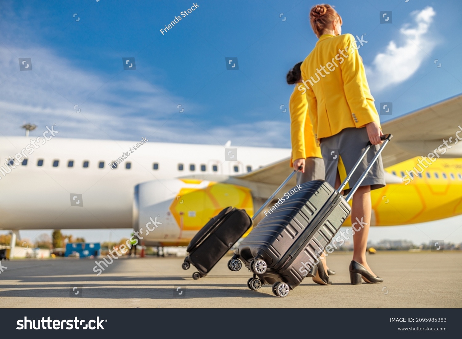 Female flight attendants with travel bags walking down airfield #2095985383