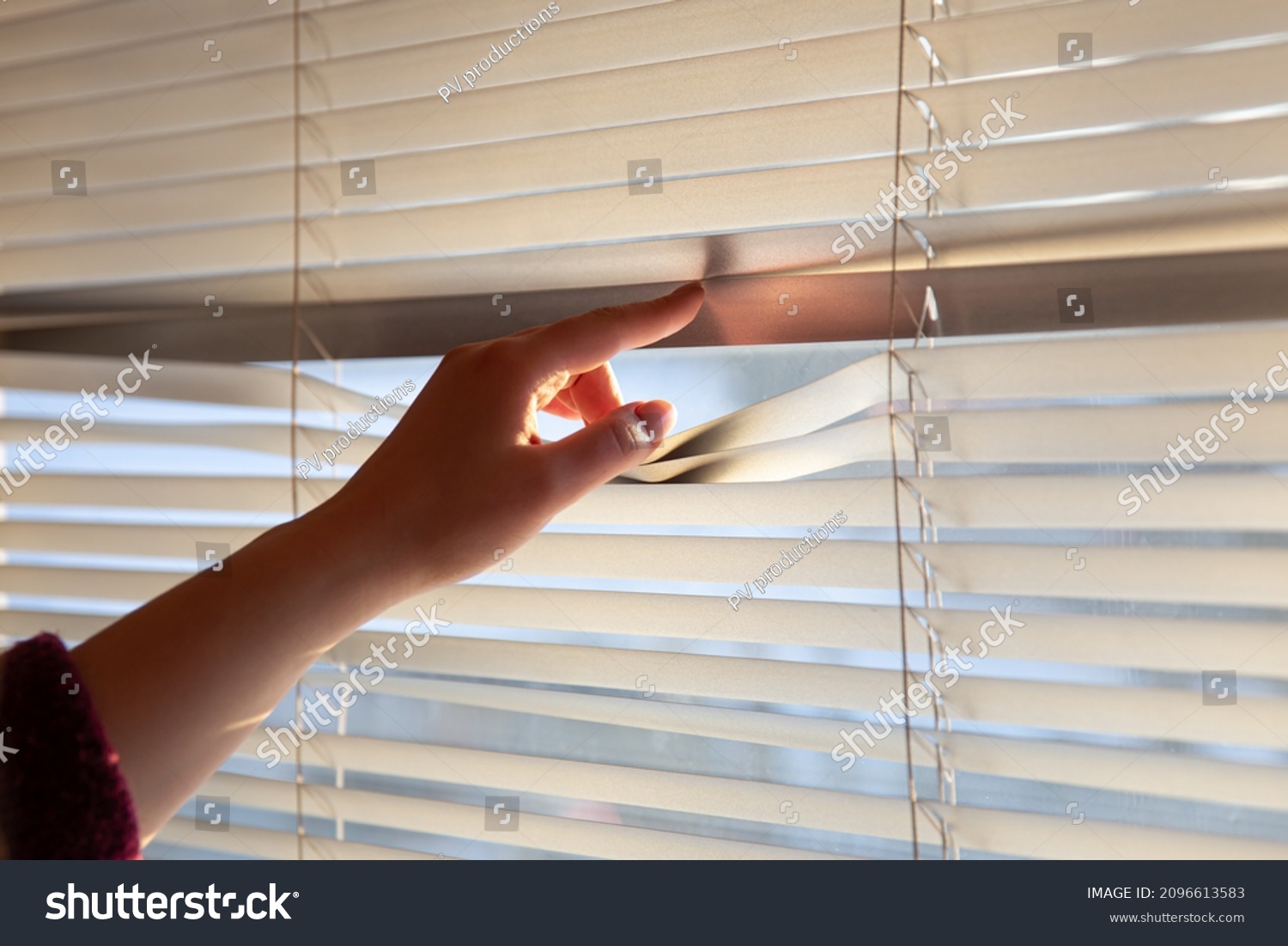 Woman's hand taking a peak through the window blinds. #2096613583