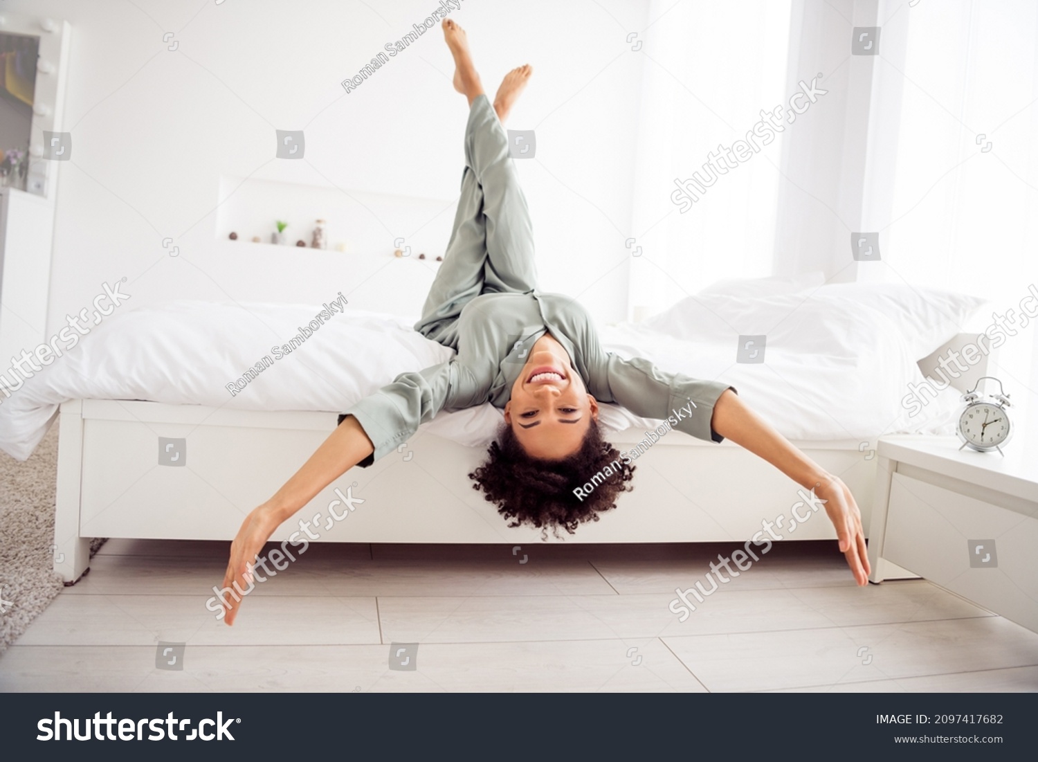 Portrait of attractive cheerful girl lying in bed having fun upside down good mood day at light home house indoors #2097417682