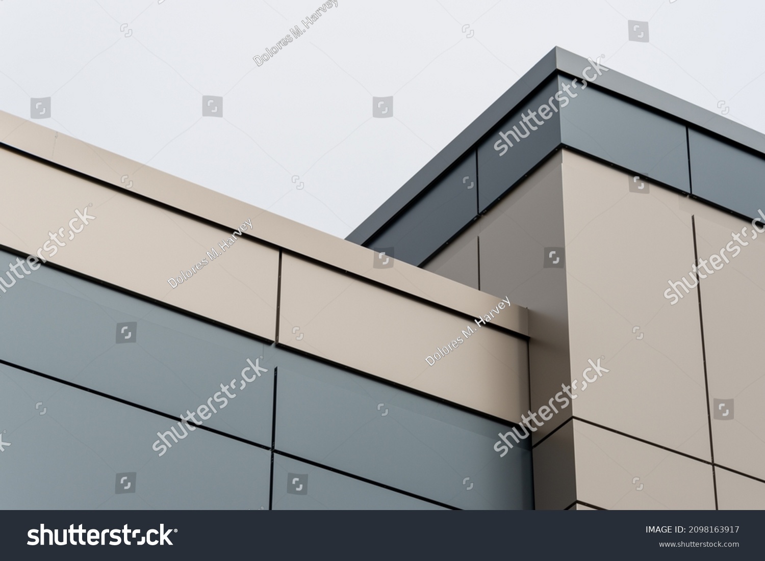 The exterior wall of a contemporary commercial style building with aluminum metal composite panels and glass windows. The futuristic building has engineered diagonal cladding steel frame panels. #2098163917