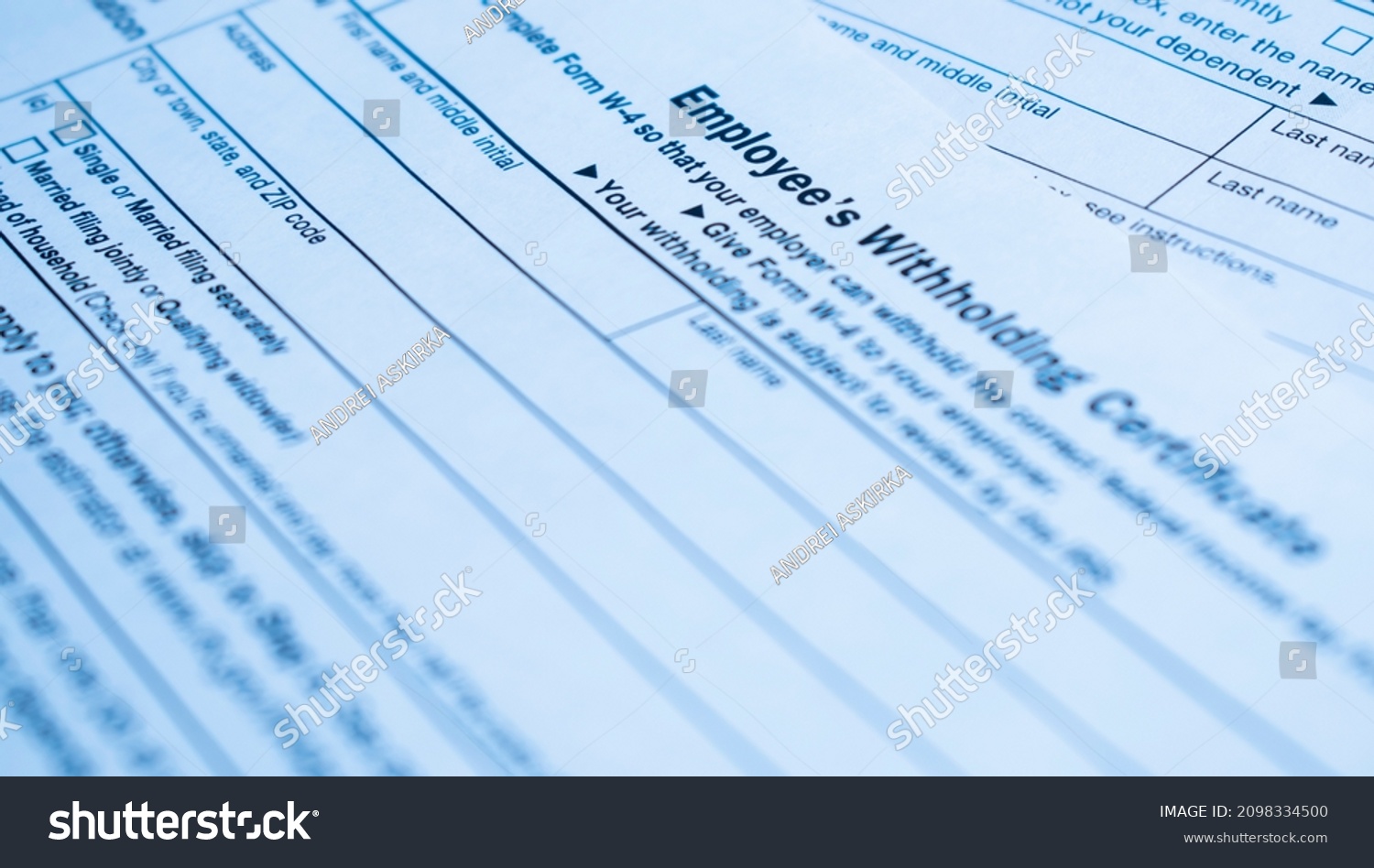 A closeup of the Form W-4, Employee's withholding certificate, and a fountain pen on a wooden surface #2098334500