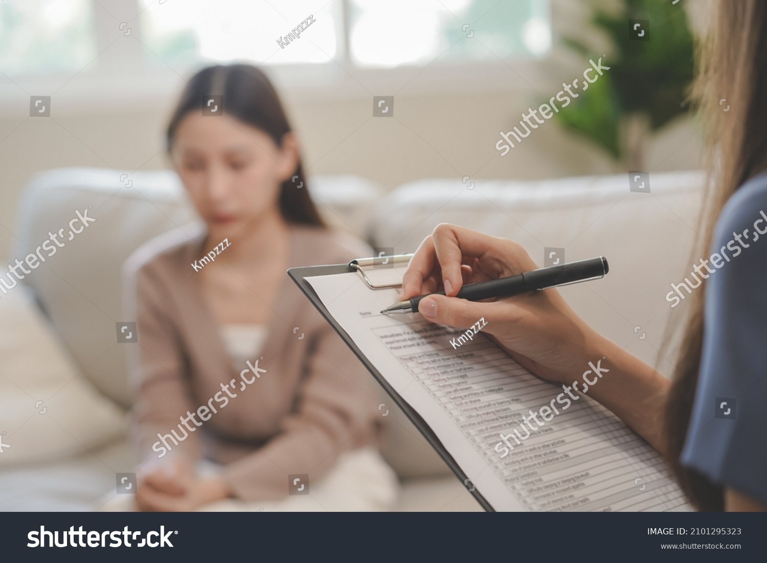 Psychology, depression. Sad, suffering asian young woman consulting with psychologist, psychiatrist while patient counseling mental with doctor woman taking notes at clinic. Encouraging, therapy. #2101295323