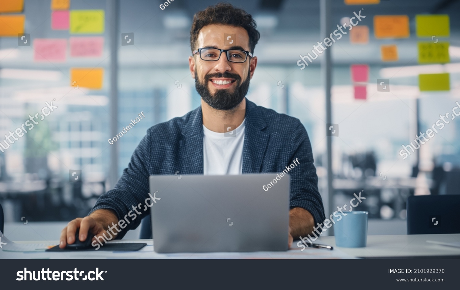 Modern Office: Portrait of Stylish Hispanic Businessman Works on Laptop, Does Data Analysis and Creative Designer, Looks at Camera and Smiles. Digital Entrepreneur Works on e-Commerce Startup Project #2101929370