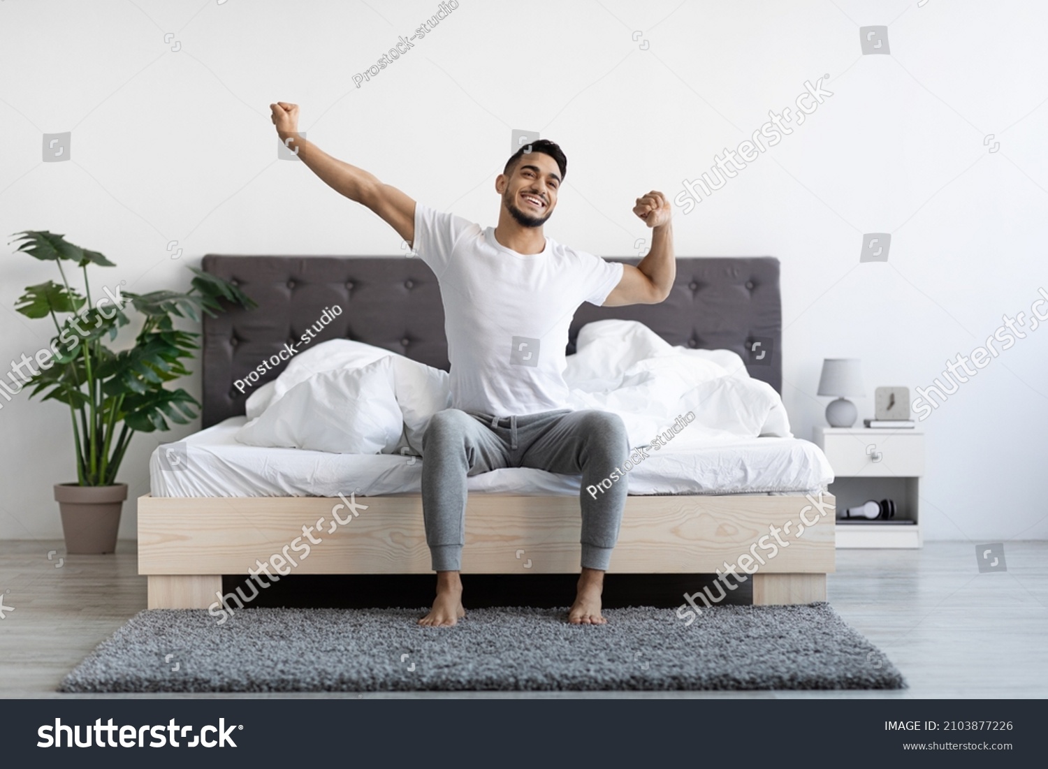 Handsome Happy Young Arab Guy Waking Up In The Morning, Sitting On Bed And Stretching After Good Sleep, Smiling Millennial Middle Eastern Man Having Good Mood, Enjoying Start Of New Day, Copy Space #2103877226