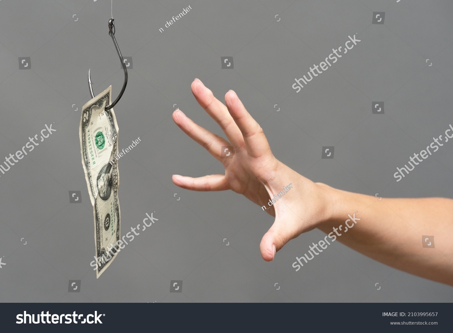 Hand trying to catch a dollar on the fishing hook close up. Financial trap concept. #2103995657