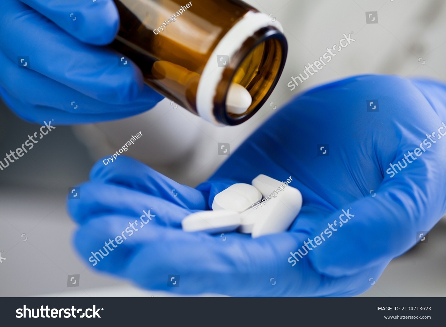 Closeup of medical worker or pharmacist hands wearing blue latex protective gloves,pouring white medicine pills on palm of hand,Coronavirus therapy treatment illustration,cure for COVID-19 new variant #2104713623