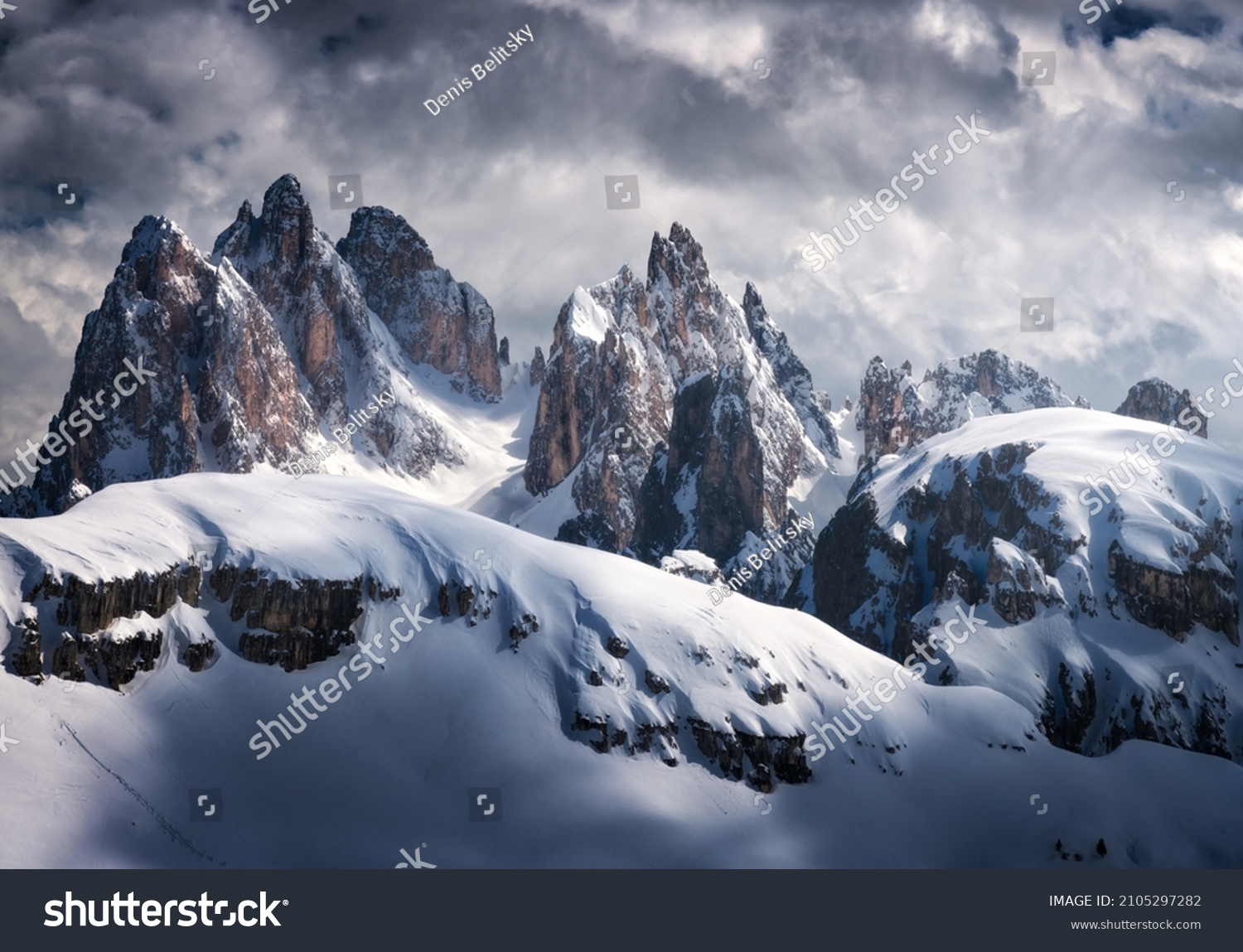 Beautiful mountain peaks in snow in winter. Dramatic landscape with high snowy rocks, overcast sky with clouds in cold evening. Tre Cime in Dolomites, Italy. Alpine mountains. Nature. Dark scenery #2105297282