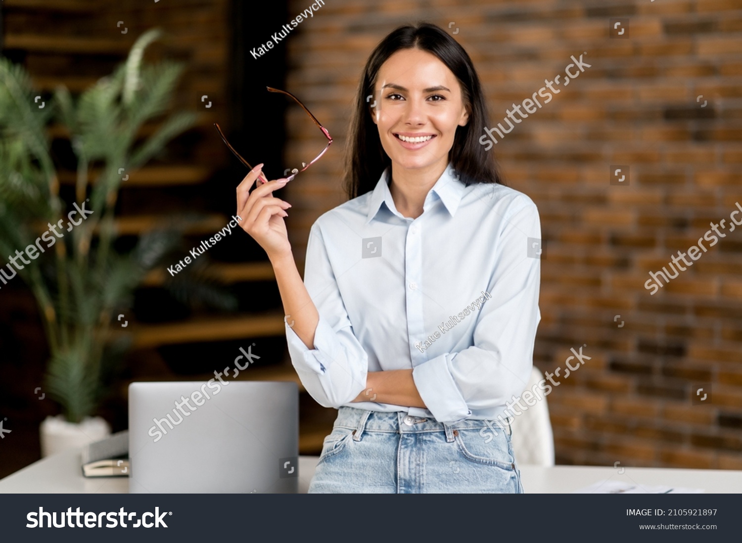 Portrait happy smart successful caucasian brunette business woman, ceo, top manager, real estate agent, stands near table in modern office, in stylish clothes, looks at camera, smiles friendly #2105921897