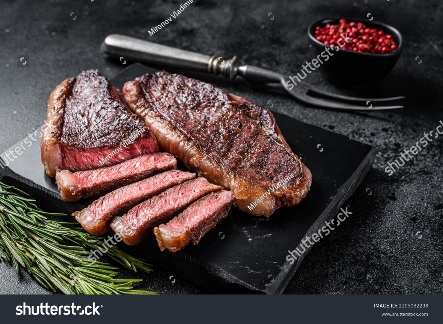 Grilled top sirloin or cup rump beef meat steak on marble board. Black background. Top view #2105932298