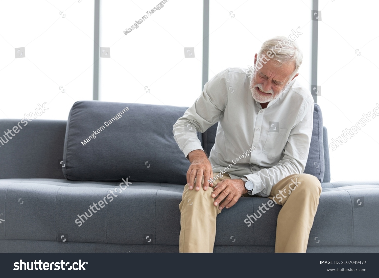 senior man suffering from knee ache on sofa #2107049477