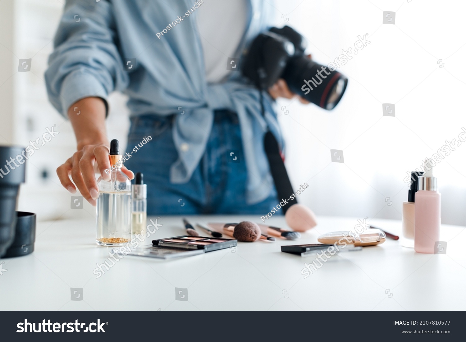 Object Photography. Unrecognizable Photographer Lady Putting Cosmetic Products On Table Making Composition And Taking Photo Of Makeup Background, Holding Camera Indoor. Selective Focus, Cropped #2107810577