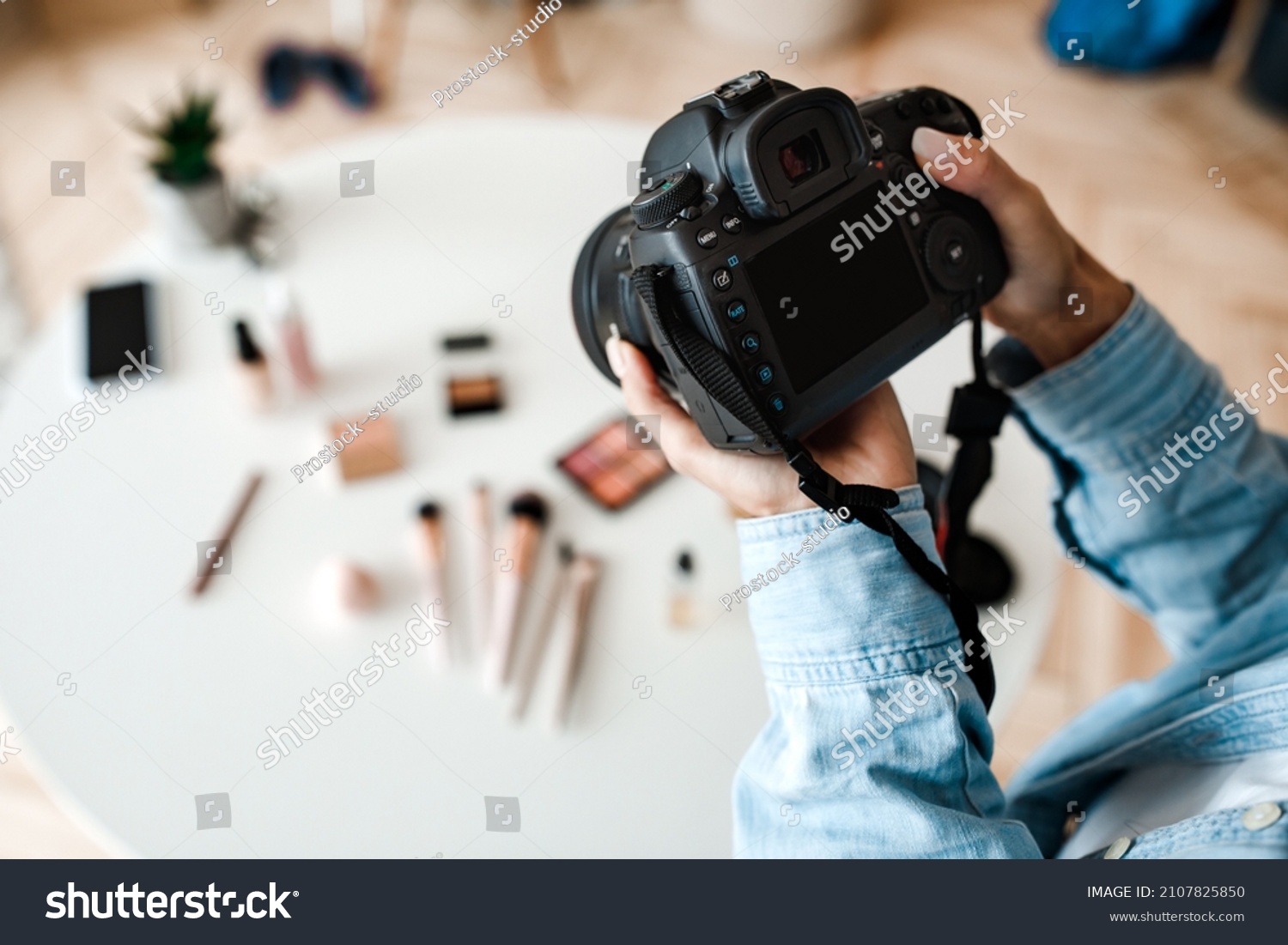 Object Photography. Unrecognizable Female Photographer Taking Photo Of Cosmetic Products On Desktop, Closeup Of Hands Holding Camera Indoors. Cropped, Selective Focus #2107825850