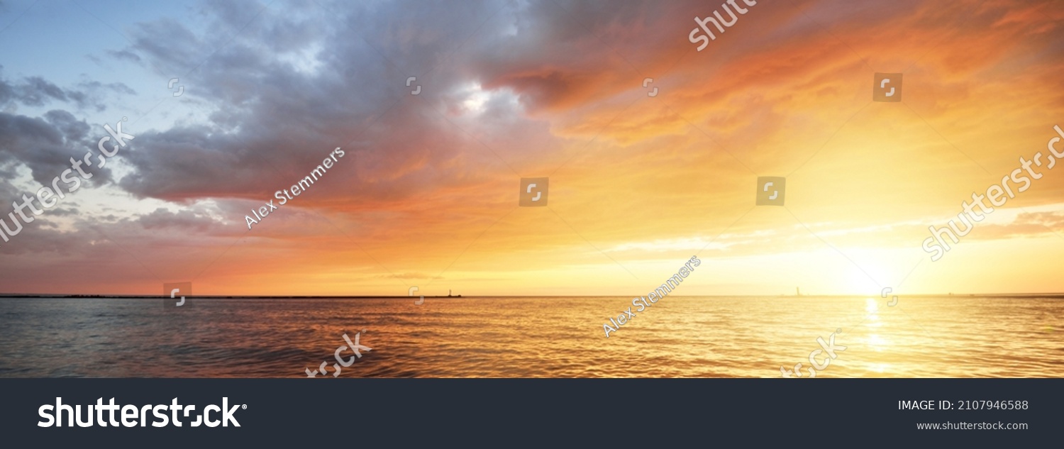 Baltic sea at sunset. Dramatic sky with glowing golden pink clouds, reflections in the water. Lighthouse. Setting sun. Epic seascape. Abstract natural pattern, texture, background, concept image #2107946588