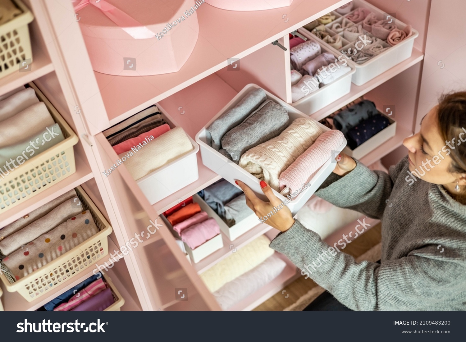 Happy young mother enjoying tidying up at female child wardrobe closet neatly folded clothes in plastic case box for comfortable vertical storage. Modern female cleanup kids cupboard Konmari method #2109483200