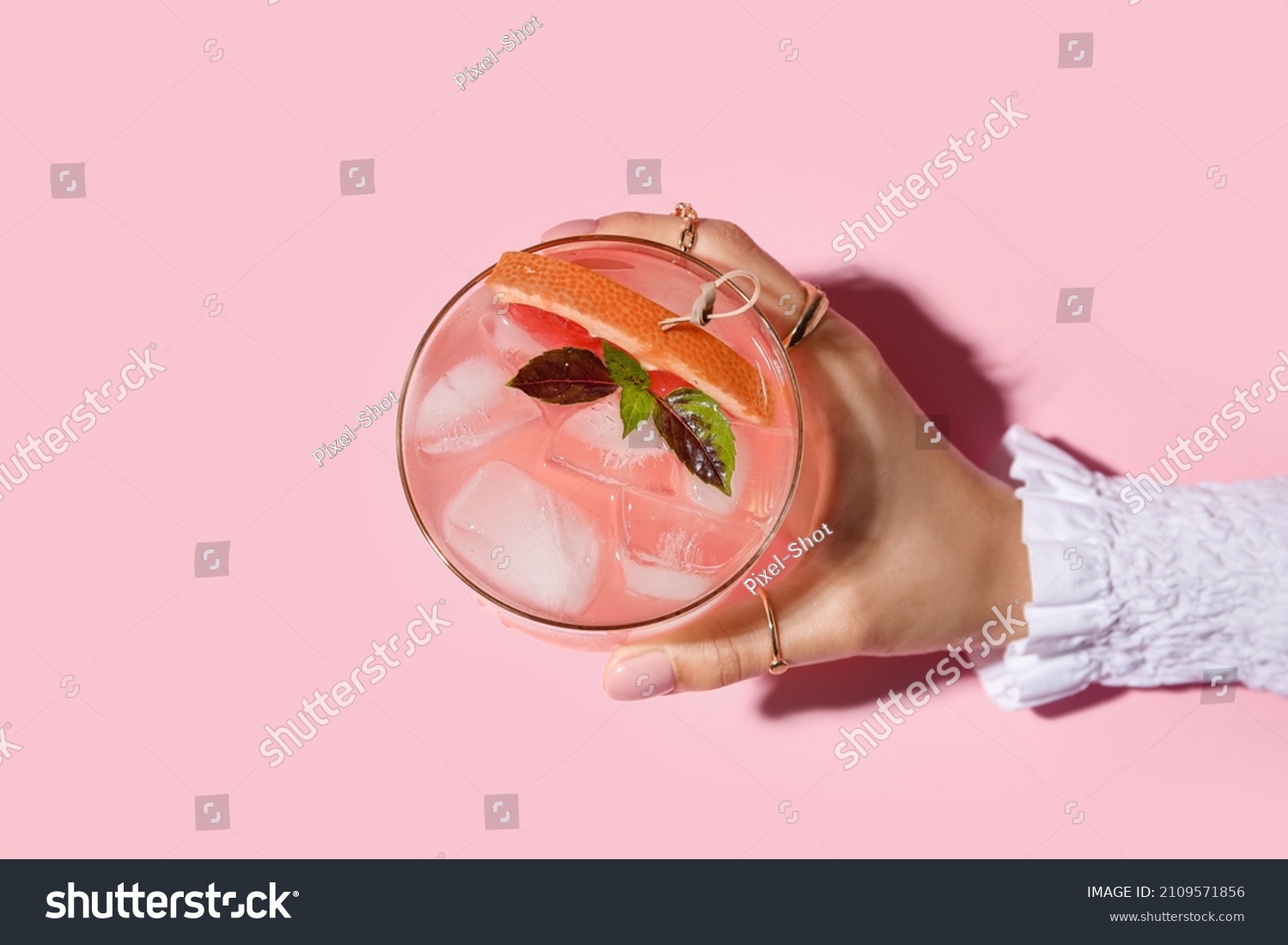 Woman holding glass of tasty grapefruit margarita on color background, closeup #2109571856